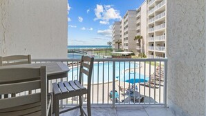 A balcony with a view of a pool and beach, a table, and chairs. - 213- Unwind, Relax & Chill in this lovely Beachfront Condo w/ W&D,FREE Bch Sv (Destin)