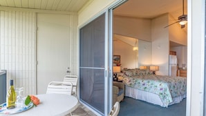 A room with a bed, a desk, and a chair. There is a sliding door leading to another room. - Napili Shores I-269 - Direct Oceanfront:  Summer and Fall Savings!  Free Activities! (Napili)