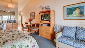 A room with a bed, a sofa, a dining table with chairs, a TV on a wooden cabinet, a fan, and artwork on the walls. - Napili Shores I-269 - Direct Oceanfront:  Summer and Fall Savings!  Free Activities! (Napili)