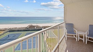 Ein Balkon mit Blick auf einen Strand und Tennisplätze.