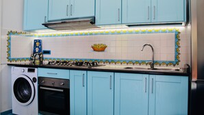 Uma cozinha com armários azuis, uma máquina de lavar, um forno e uma pia.
