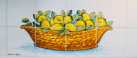 Pared de azulejos con una cesta de limones y hojas.