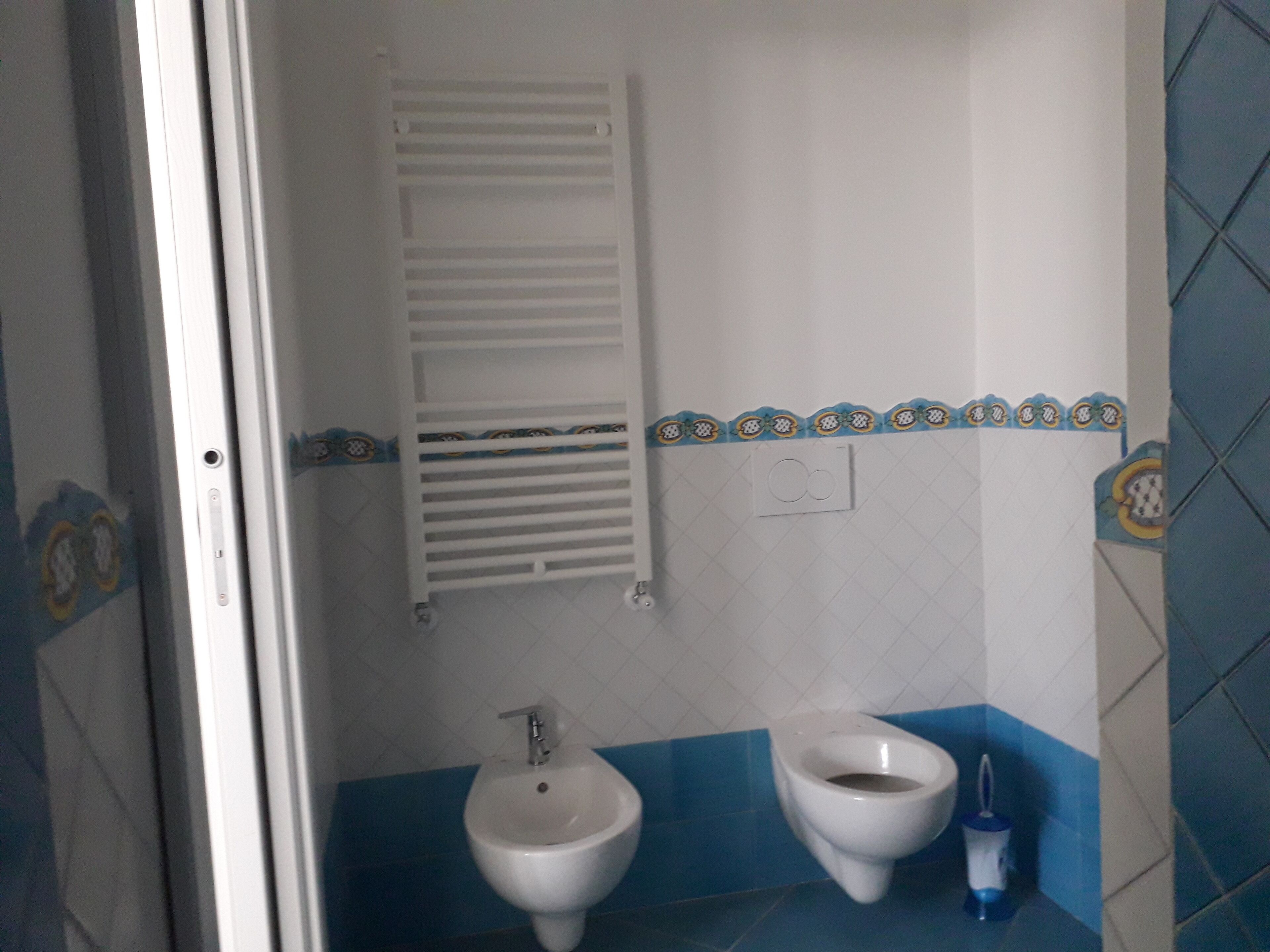A bathroom with a bidet, a toilet, and a towel rack.
