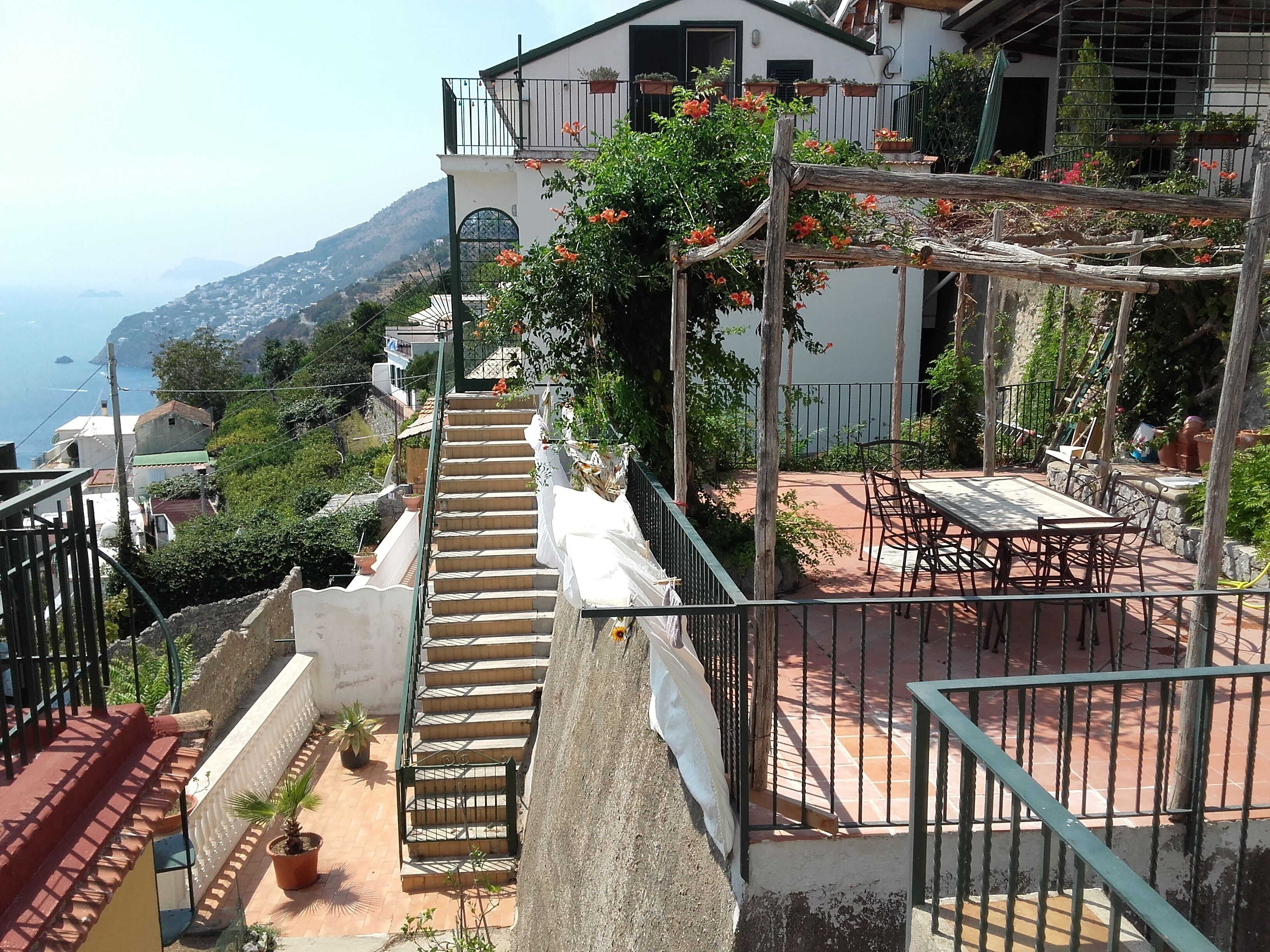 Un edificio residenziale con una scala che conduce a un balcone affacciato su una zona costiera.