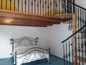 Une chambre à coucher avec un lit, un escalier en bois et un mur blanc.