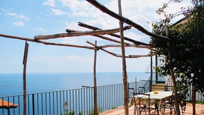 Um terraço com mesa e cadeiras, com vista para o mar.