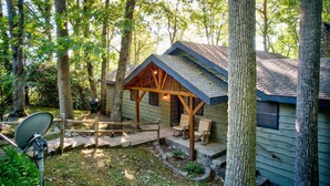 Eine rustikale Holzhütte mit Veranda, umgeben von hohen Bäumen.