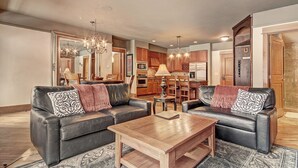 Ein modernes Wohnzimmer mit zwei Ledersofas, einem Holztisch und einem Essbereich mit Holzkästen und einer Kandelaber.