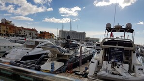 Un port de plaisance où sont amarrés plusieurs yachts, une enseigne indiquant « Cool Charters », et un bâtiment en arrière-plan.