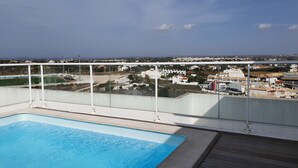 Une piscine sur le toit offrant une vue dégagée sur un quartier résidentiel et, au loin, sur un terrain de sport.