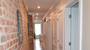 A hallway with wooden flooring, white doors, and a brick wall. - Local Culture themed Historic luxury condo, 2 blocks from French Quarter (New Orleans)