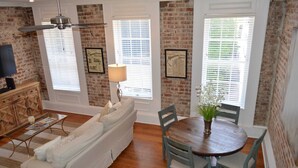 A dining area with a wooden table and chairs, a white sofa, and a ceiling fan. - Local Culture themed Historic luxury condo, 2 blocks from French Quarter (New Orleans)