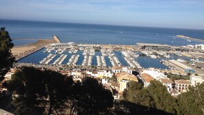 A marina with numerous boats docked, a building labeled 'GALERA PORT', and a clear view of the sea.