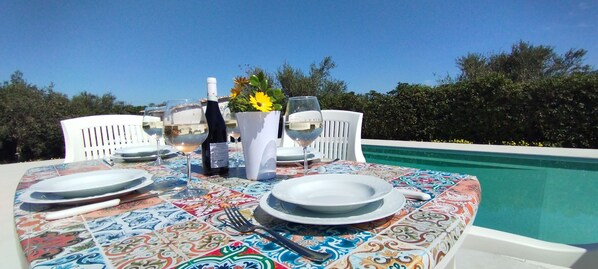 A table set for two with white plates, wine glasses, and a bottle of wine, overlooking a pool. - Flower Villa with large private pool and wellness for exclusive use (Carini)
