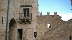 Un bâtiment en pierre doté d’un balcon, d’une porte et d’une petite fenêtre.