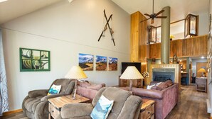 A cozy living room with a fireplace, wooden furniture, and a ceiling fan. - Spacious Updated Retreat/Sleeps 14/On Shuttle Route/Pool and Hot Tub Access (Keystone)