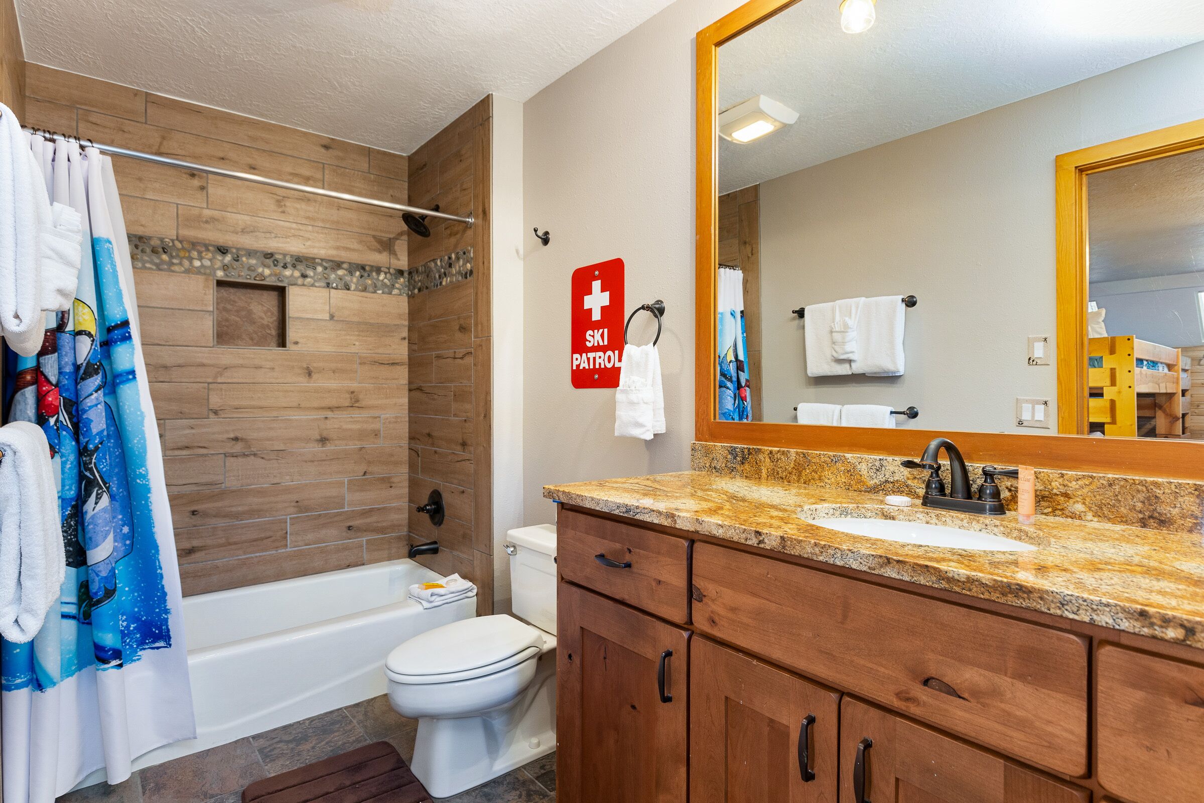 Ein Badezimmer mit einer Holzwand, einer Badewanne, einer Toilette, einem Waschbecken mit Marmorplatte und einem Spiegel.