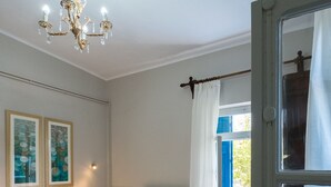 Ein Schlafzimmer mit einem weißen Bett, einem Chandelier und einem fensterbepflanzten Fenster.