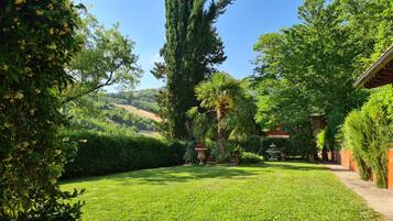 Ein gepflegter Garten mit verschiedenen Bäumen und freiem Blick auf die umliegende Landschaft.