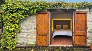 Une chambre à coucher avec un lit, des volets en bois et un mur en pierre.
