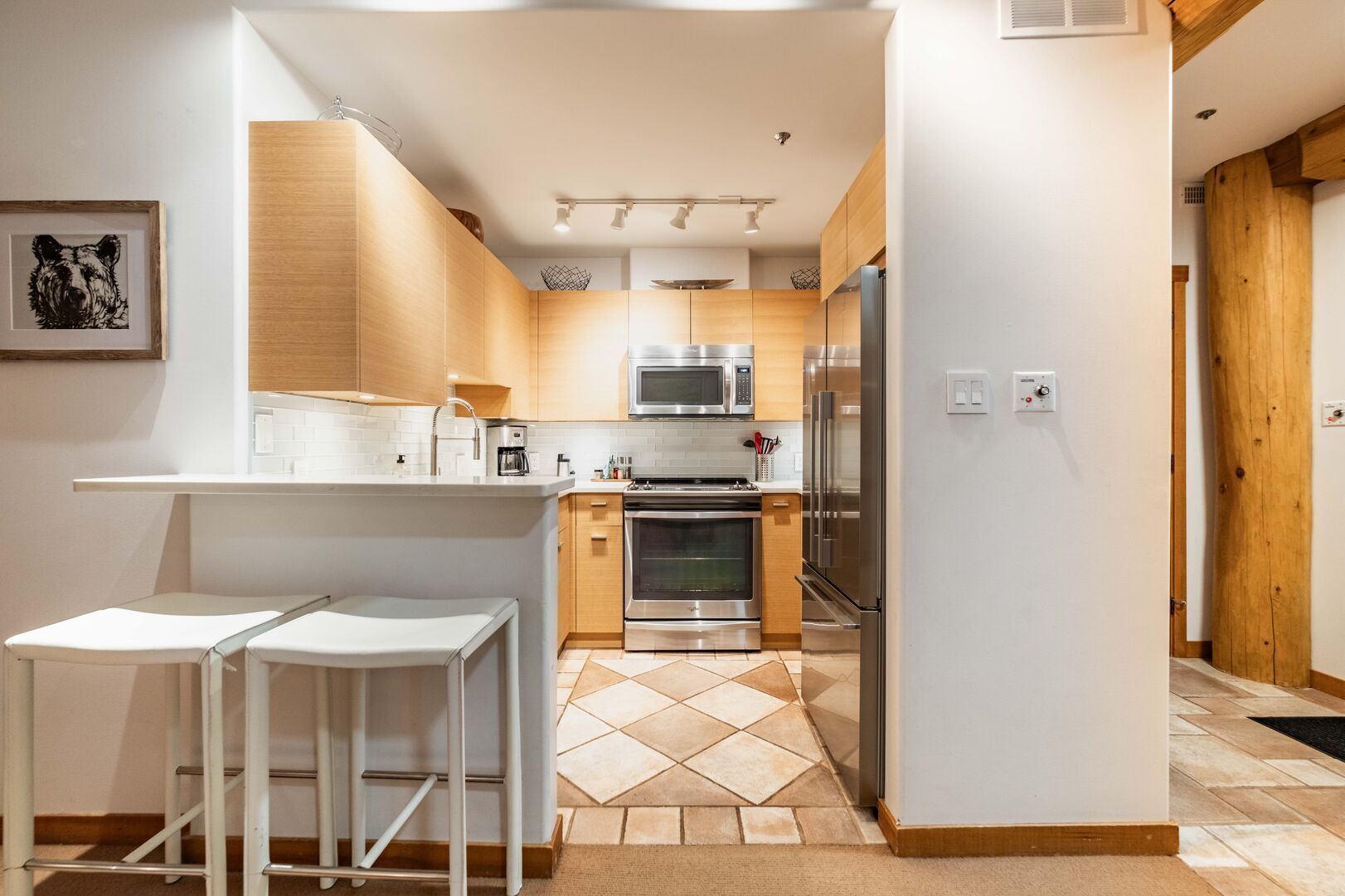 A modern kitchen with wooden cabinets, stainless steel appliances, and a tiled backsplash.