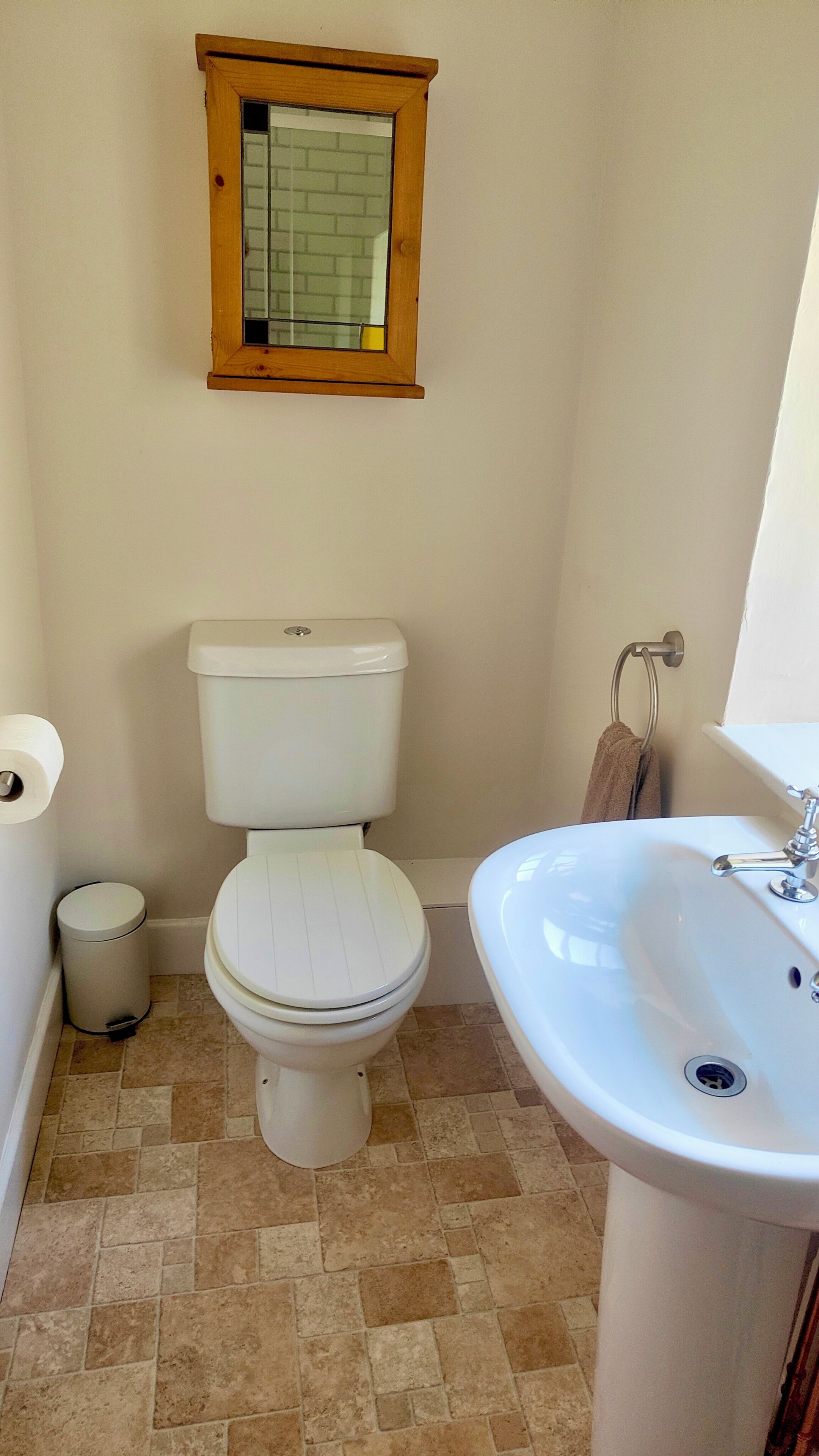 Une salle de bain équipée d’un WC, d’un lavabo, d’une fenêtre et d’un porte-serviettes.