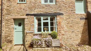 A stone building with a tiled roof, a clock, and a sign reading 'Stable Cottage.' - "Wonderfully Situated in the heart of Exmoor" (Exford)