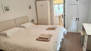 A hotel room with a bed, a wardrobe, a desk, and a bathroom visible through an open door.