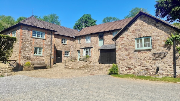 A stone building with multiple windows and a gravel driveway.