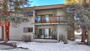 A two-story house with a balcony, large windows, and a snow-covered ground. - Ground Floor Condo, Courtyard View, Pool & Hot Tub, Shuttle to Slopes (Keystone)