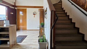 Un hall d’hôtel avec un comptoir d’accueil en bois, un escalier et une plante en pot.