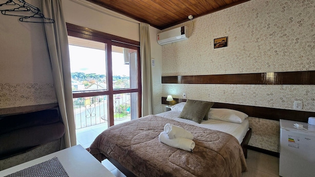 Une chambre d’hôtel équipée d’un lit, d’un bureau, d’un climatiseur et offrant une vue sur l’extérieur.