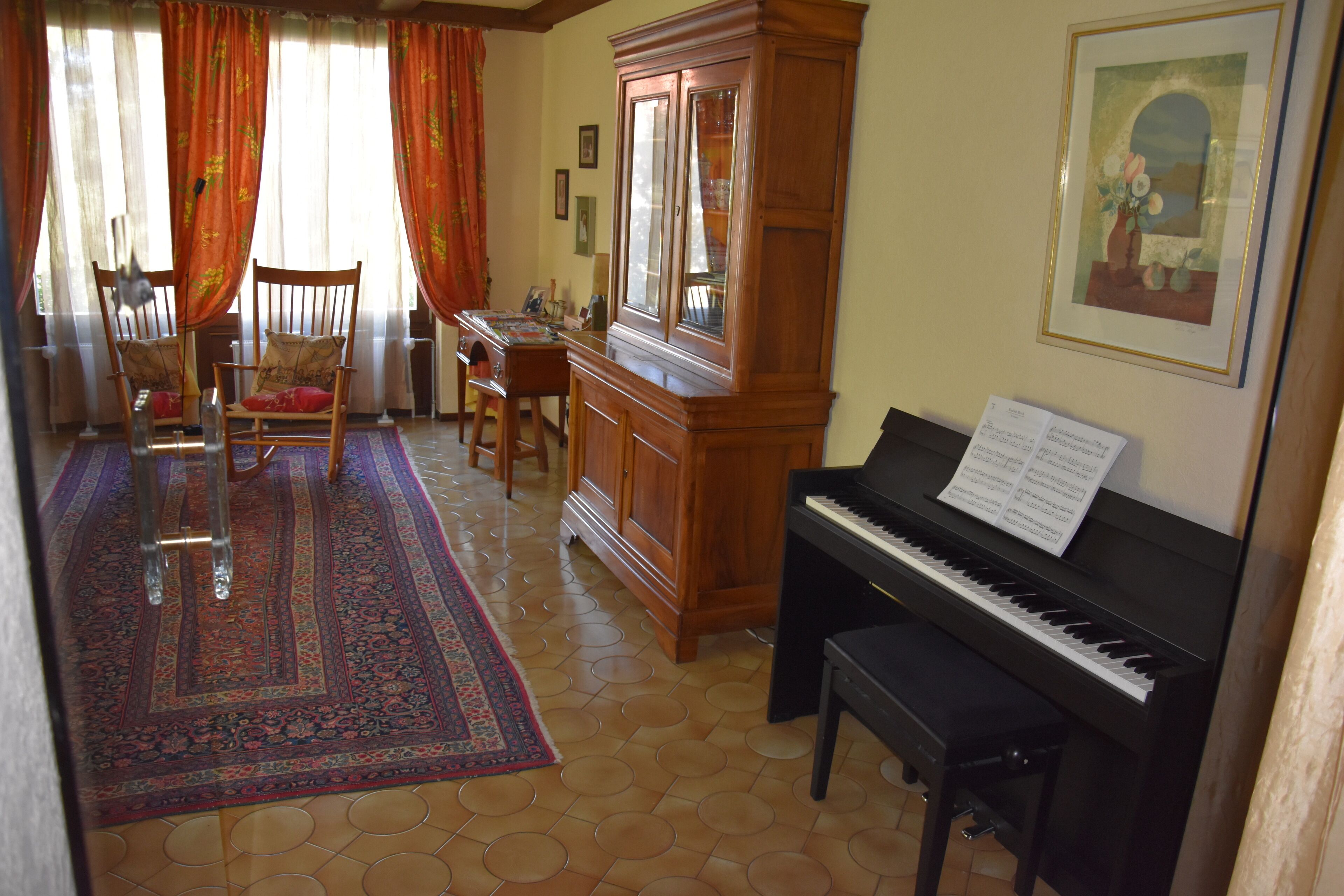 Une pièce avec un piano, un meuble en bois, une chaise et un tapis.