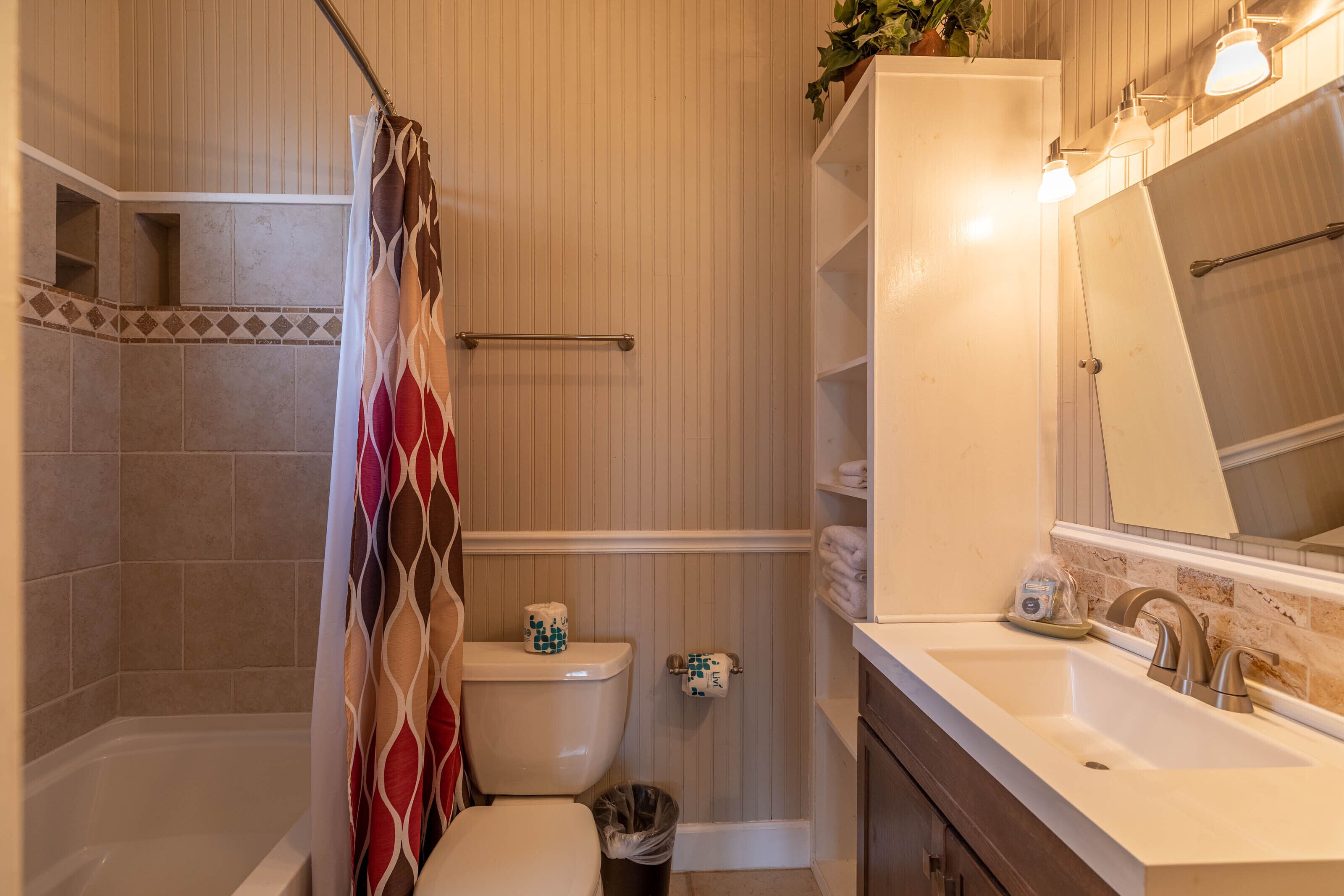Een badkamer met een douche, toilet, wastafel en een spiegel.