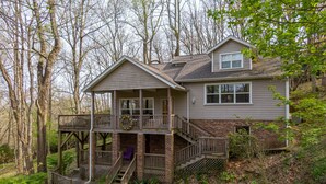 A two-story house with a balcony, a covered porch, and a staircase leading to the upper level. - A Treetop Escape: All Nights $199! App Ski Mtn home with spacious decks! (Blowing Rock)