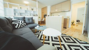 A modern living room with a grey sofa, a small white table, and a patterned rug. - Feel in Sarajevo Apartment + Parking (Sarajevo)