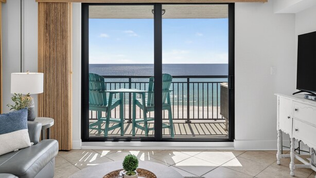 Une chambre avec un balcon, un canapé, une télévision et une table agrémentée d’une plante.