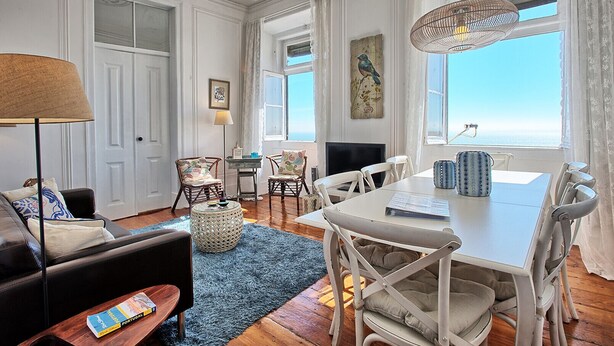 A spacious living room with a large window, a dining area, and a cozy seating area. - RM3 - River View | Alfama | AC | 4BR | 3 BATH Sleeps 9 (Lisbon)