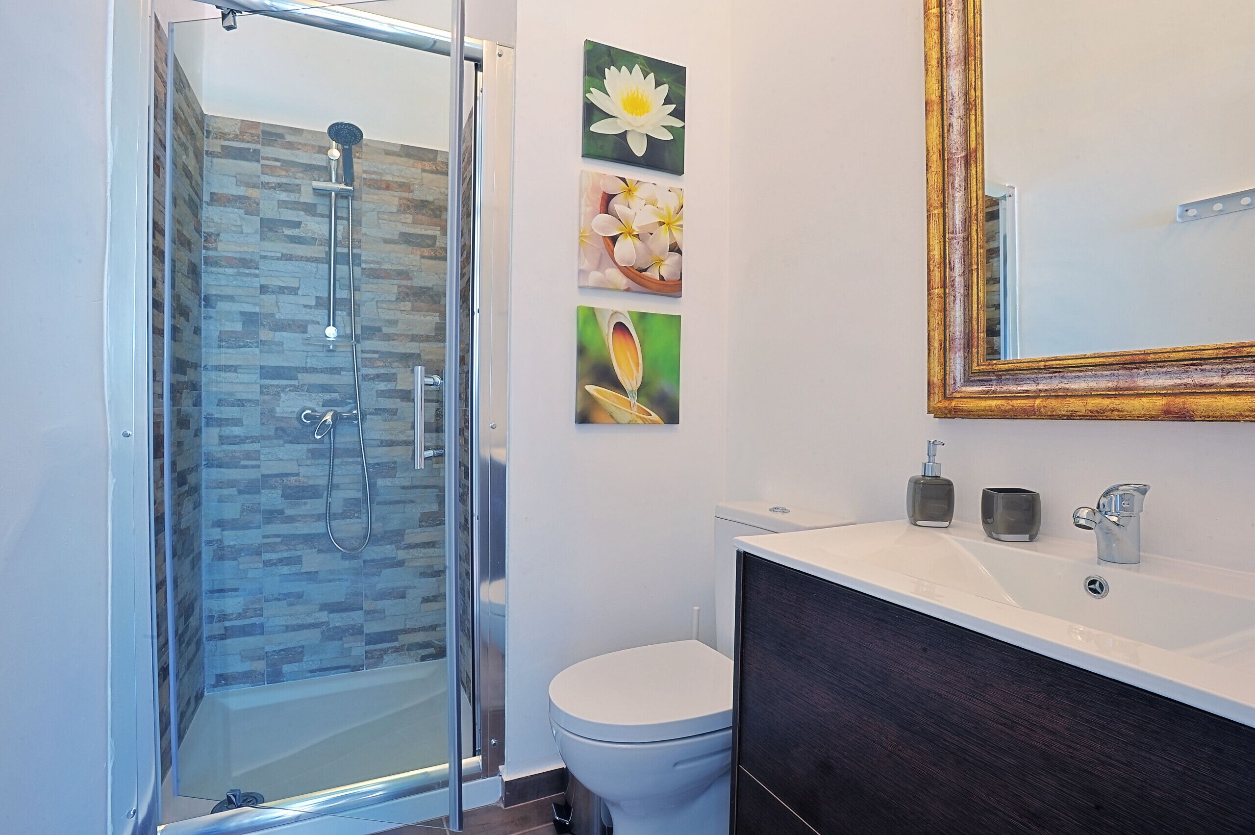 Une salle de bain moderne dotée d’une douche à parois de verre, de toilettes et d’un meuble-lavabo avec un miroir.