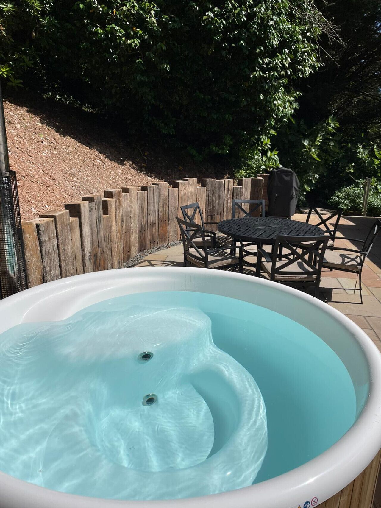 Een hottub met een houten terras en tuinmeubilair.