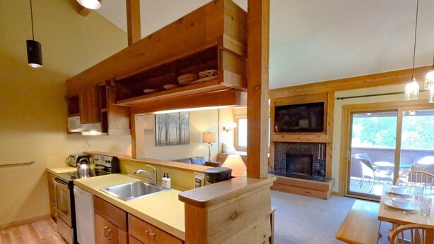 A kitchen with wooden cabinets, a built-in oven, and a dining area with a table and chairs. - JHRL - Mtn Alder 824, A cozy 2 bedroom condominium located in The Aspens (Wilson)