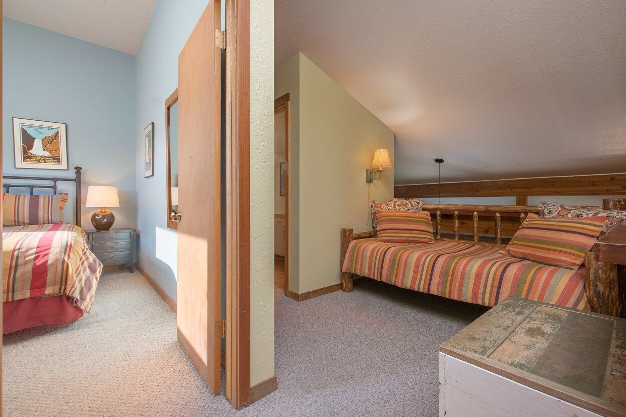 A bedroom with a bed, a nightstand, a lamp, and a wooden headboard.