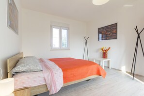 Ein Schlafzimmer mit Bett, Nachttisch, Fenster, Wandbild und Stehlampe.