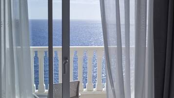Enjoy the ocean view from this balcony with a balustrade and chair.