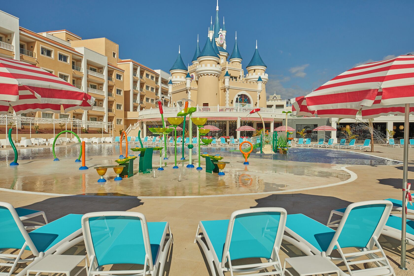 A water park with a castle, lounge chairs, and umbrellas.