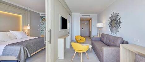 A modern hotel room with a bed, a sofa, a desk, and two chairs.
