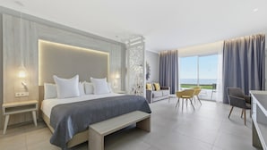 Un dormitorio moderno con una cama grande, mesitas de noche, un banco, un sofá y un comedor con sillas.