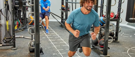 A gym with exercise equipment and a person running.