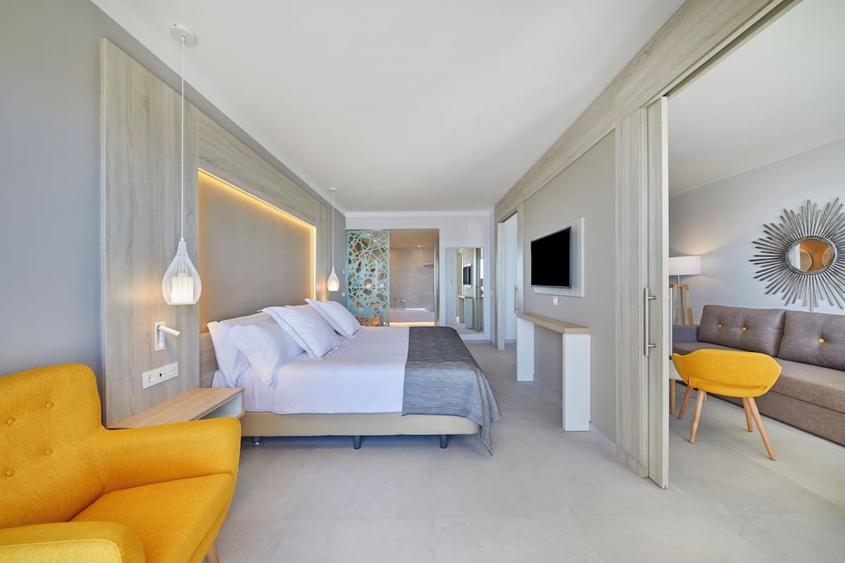 Une chambre d’hôtel moderne équipée d’un lit, d’un canapé, d’une télévision et d’un miroir décoratif.