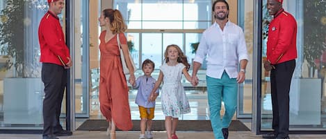 A family walking through a hotel entrance with staff members.
